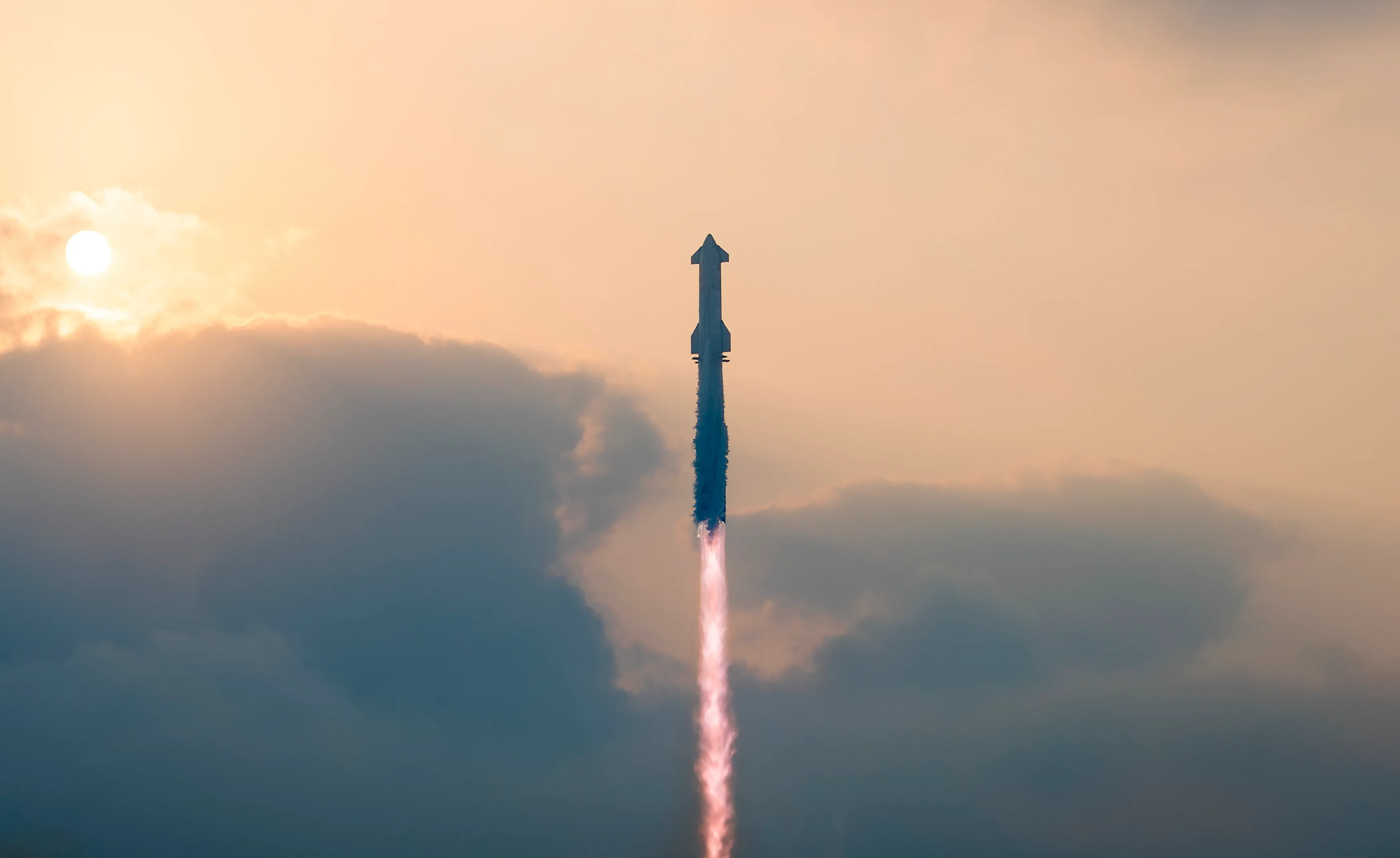 A rocket takes off in the sky against a cloudy background, the sun partially visible.