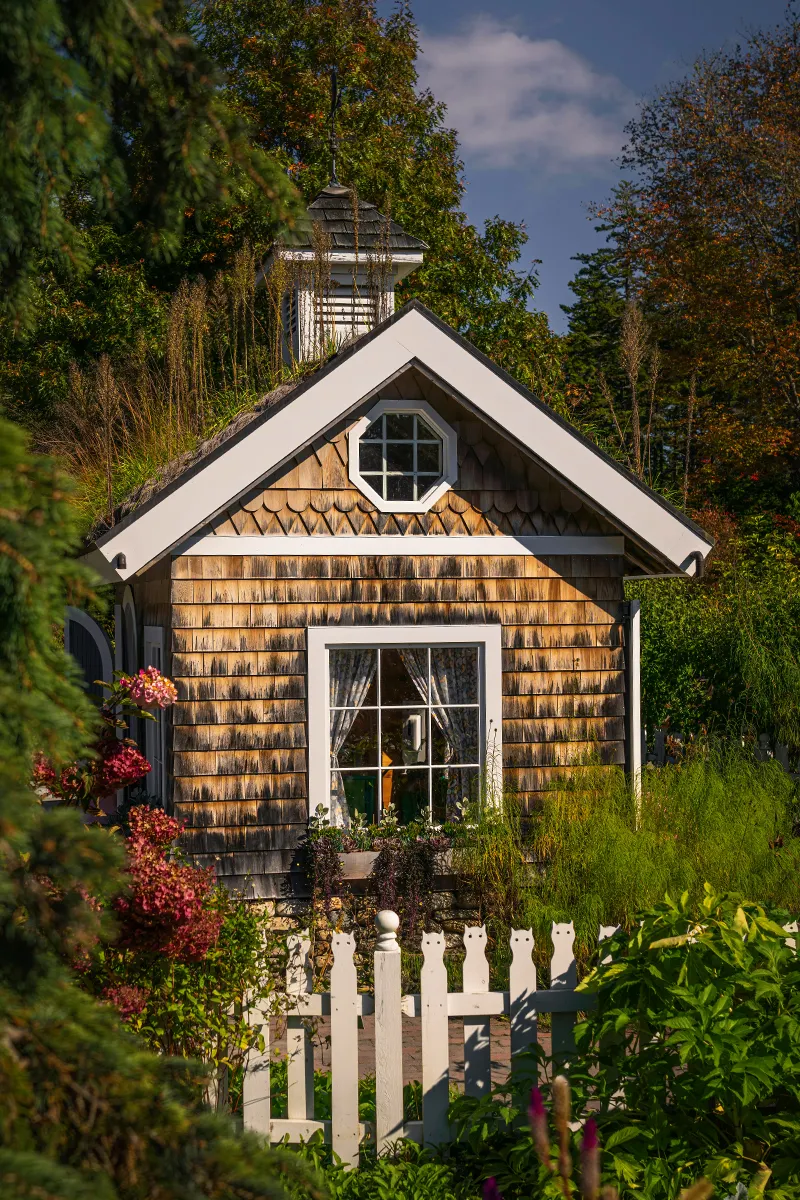 White and brown house next to green trees