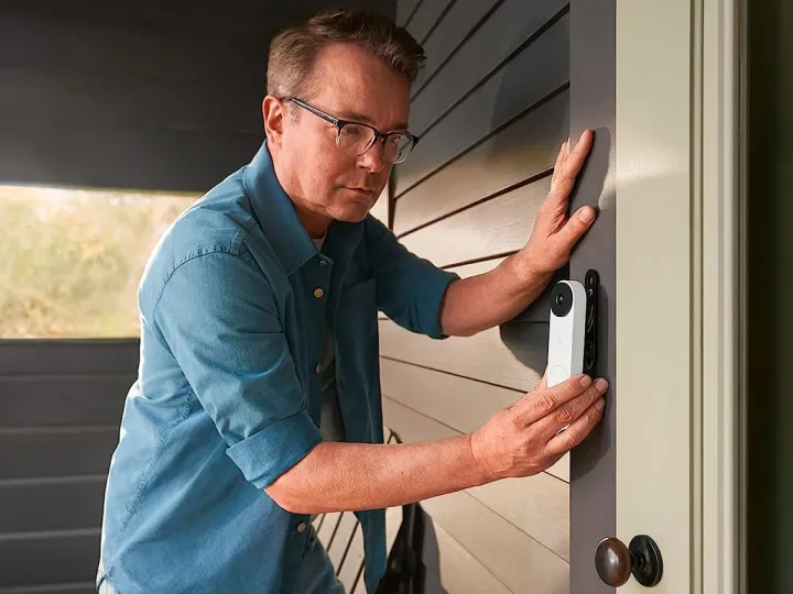 Google's new home AI continues to literally see things 2 A man installs a wired model of the Google Nest Doorbell near his front door.