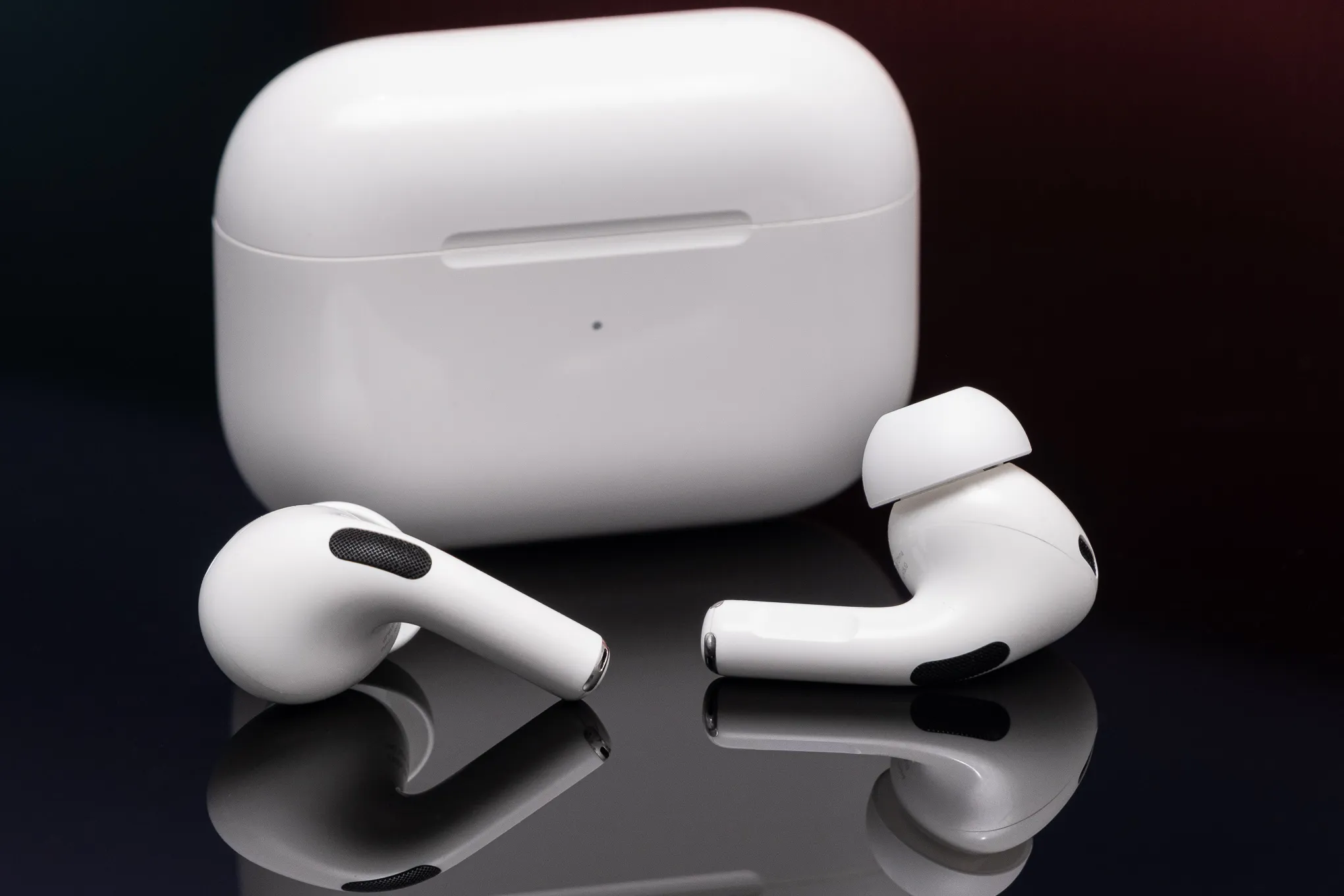 Apple's second-generation AirPods Pro are depicted on a reflective black surface.