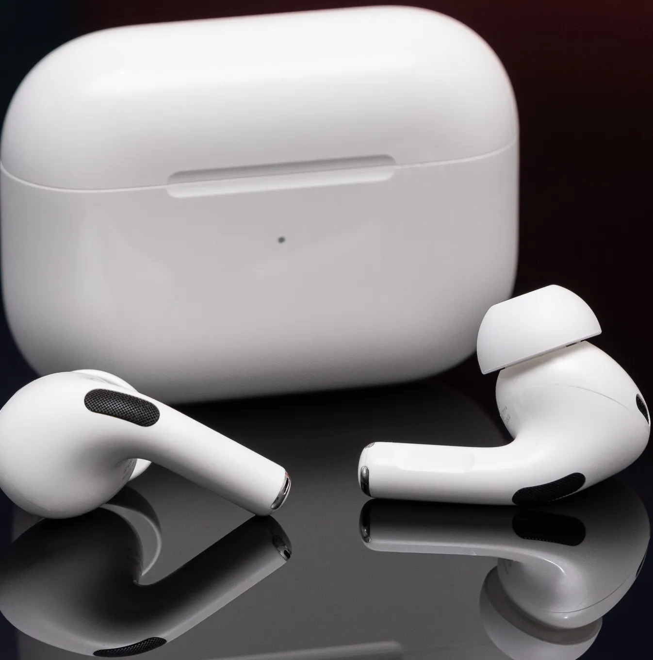 Apple's second-generation AirPods Pro are depicted on a reflective black surface.